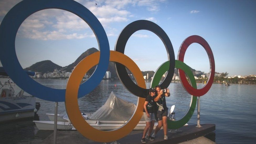 Members of the New Zealand rowing team take photos in front of the Olympic rings at the Rodrigo de Freitas Lagoon in Rio de Janeiro (01 August 2016)
