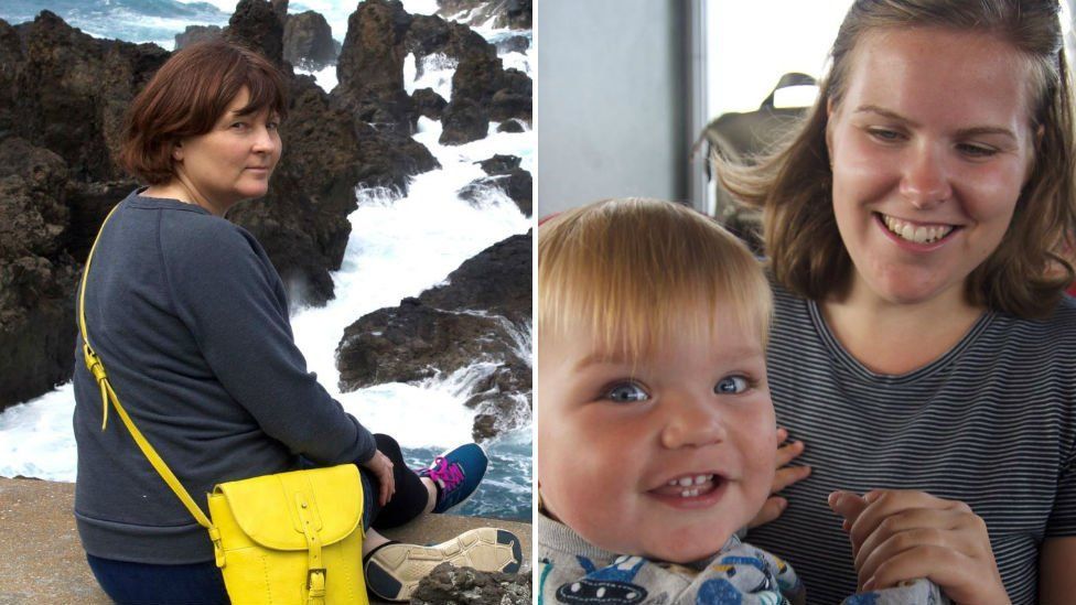 A woman sitting above a rocky sea turning to look over her shoulder and a second woman smiling at a toddler who is turning to look at the camera