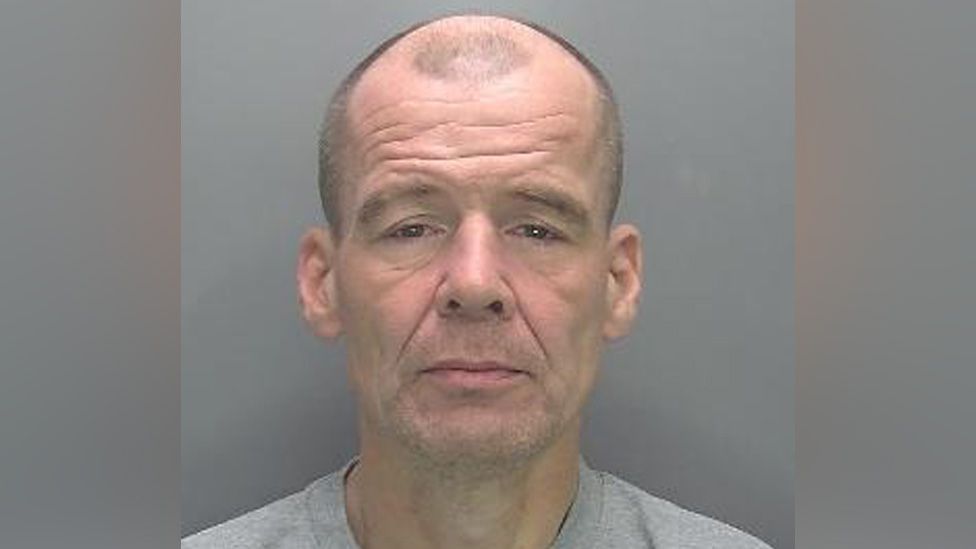 Terry Lewis in custody, appearing bald and wearing a grey jumper