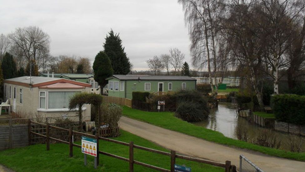 Several static caravans in front of a river at Cogenhoe Mill Holiday Park