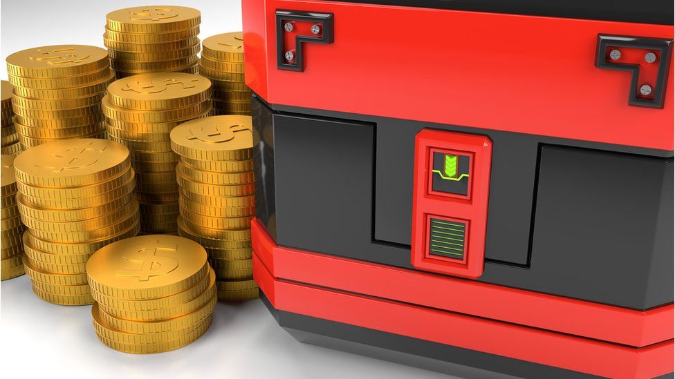 A gaming box beside a stack of gold coins