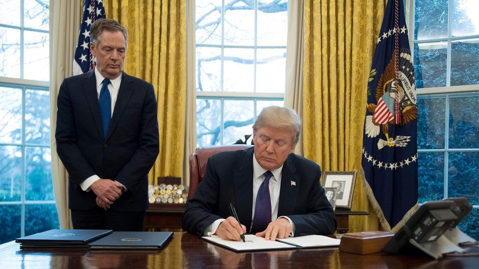 Robert Lighthizer watches as President Donald Trump signs a document in the Oval Office