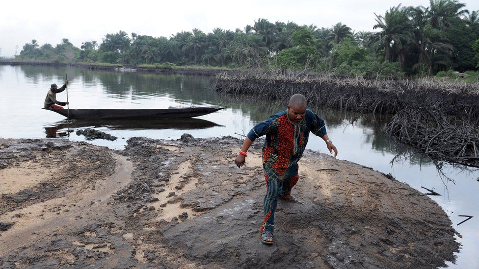 A man walks on slippery spilled crude oil on the shores and in the waters of the Niger Delta swamps of Bodo,