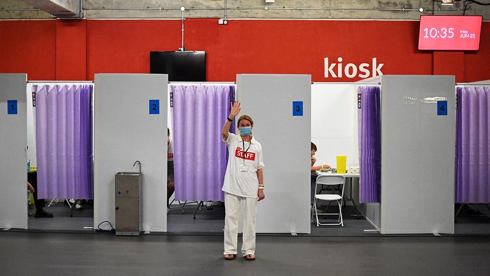 A member of staff calls over the next person to receive a dose of a Covid-19 vaccine inside a temporary vaccination centre set up at the Emirates Stadium, home to Arsenal football club, in north London - 25 June 2021