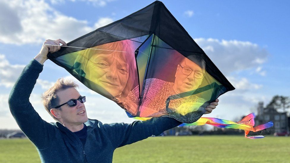 Luke Jerram holding a kite with the faces of two people on it