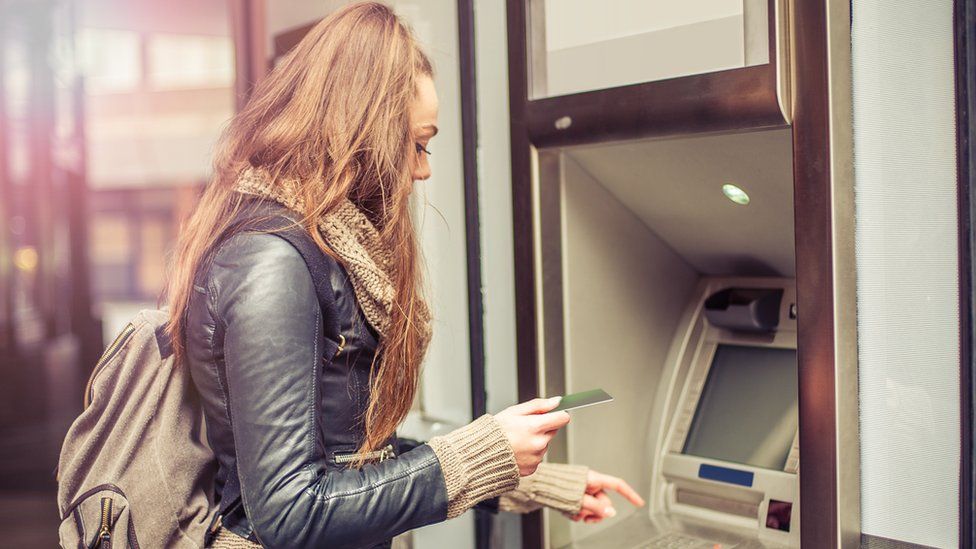 Young woman withdrawing cash from atm