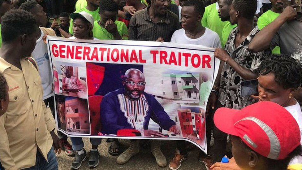 Demonstrators hold a poster portraying Liberian President George Weah as they gather outside the Liberian Mansion in Monrovia on June 7, 2019 during an anti-government march to protest at inflation and corruption.