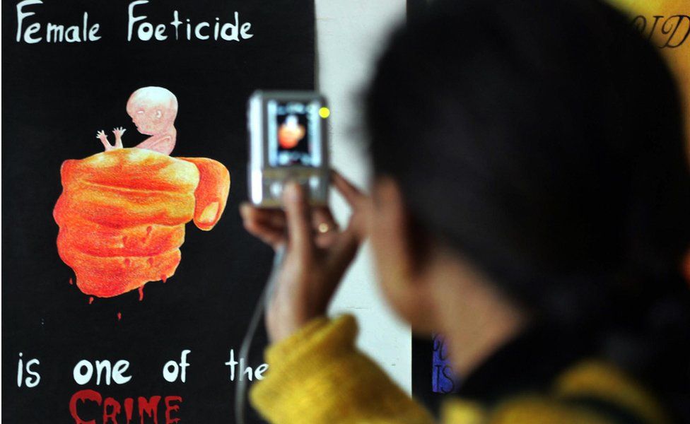 A young girl, Aman Kaur takes a photograph of paintings displayed during the opening of the art exhibition 'Female Foeticide' at Virsa Vihar hall in Amritsar on January 25, 2009.
