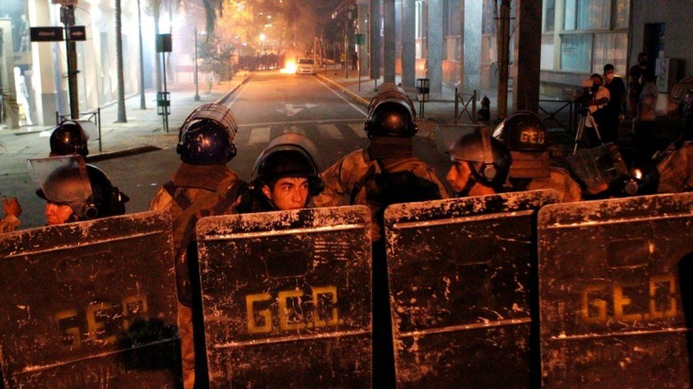 Riot police officers stand in formation during clashes in Asuncion