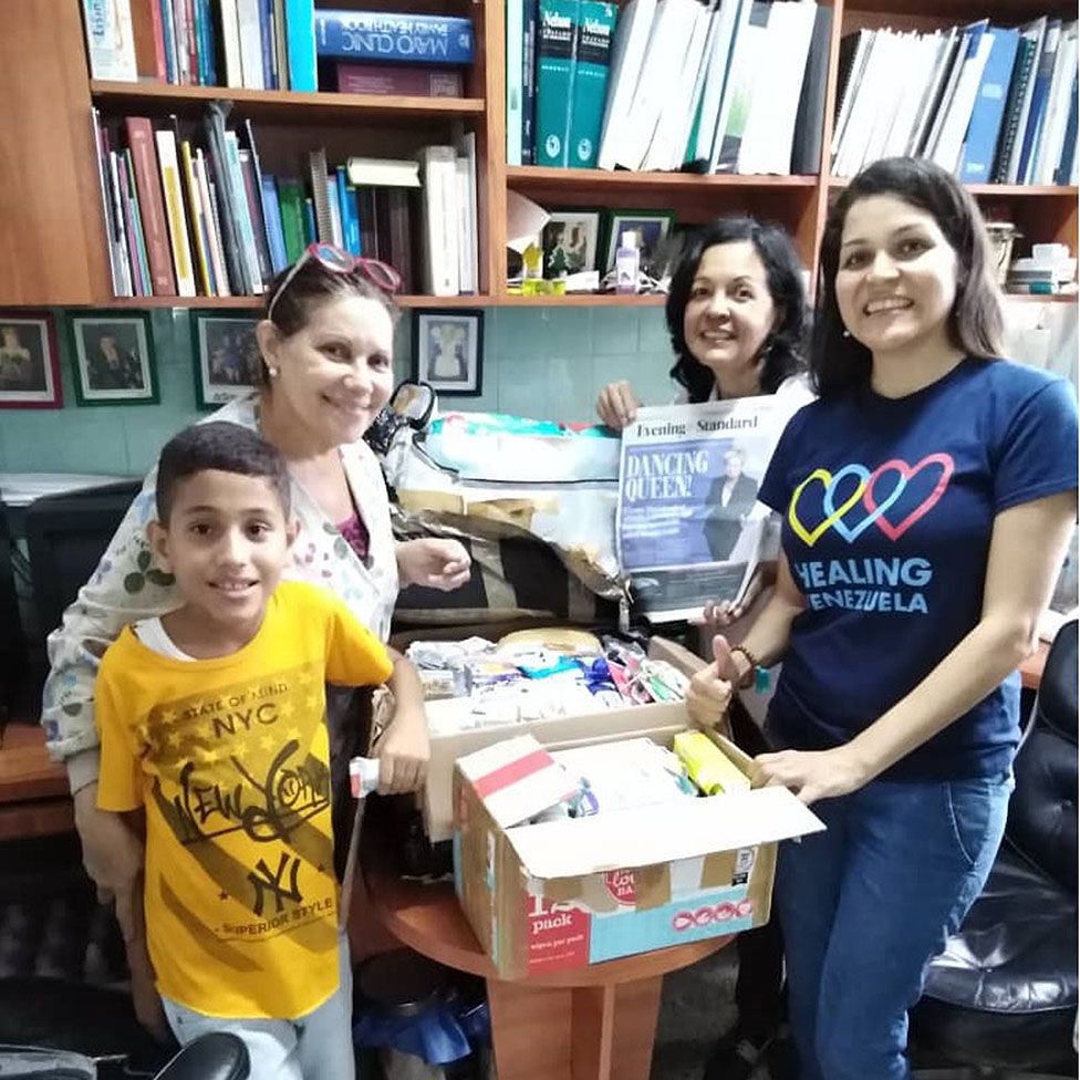 Venezuelans receiving supplies from UK charities show a British newspaper as proof