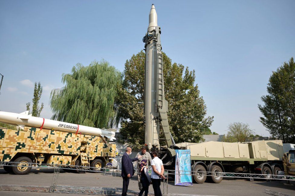 An Iranian family speaks with a member of the Islamic Revolution Guard Corps (IRGC) as they stand in front of a Qiam short-range ballistic missile, while visiting the Holy Defene Garden Museum in Tehran on 29 September 2020