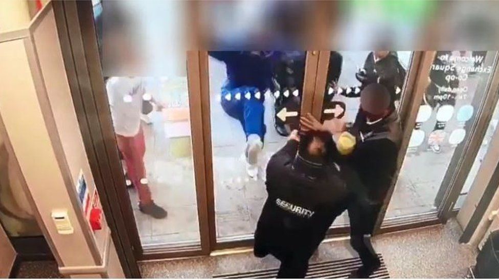 People outside a Co-op store kick the doors
