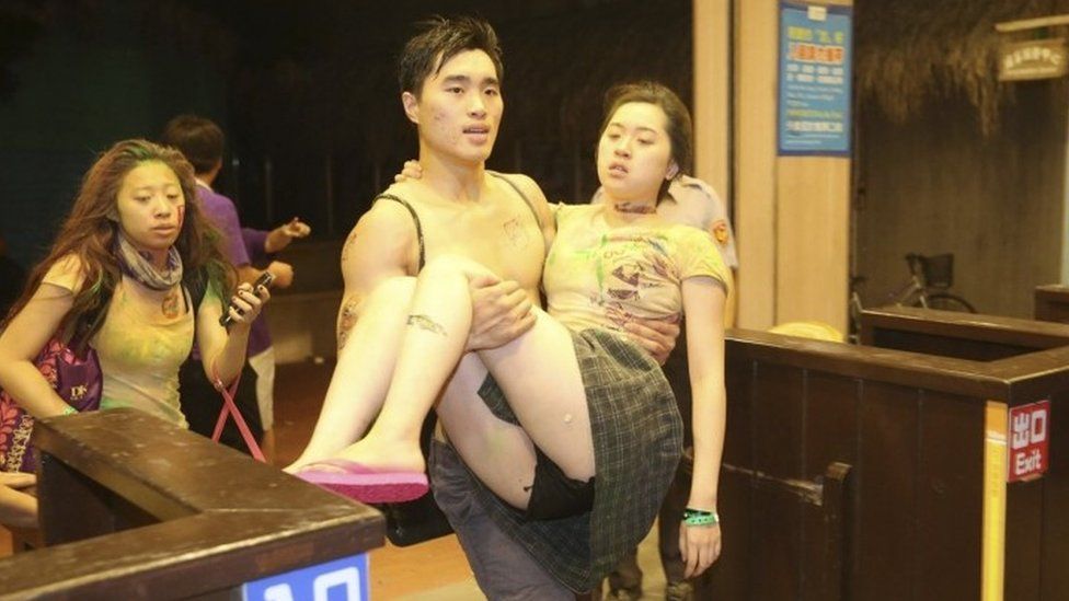 A man carries an injured victim after the explosion at the Formosa Water Park in Taipei, 27 June