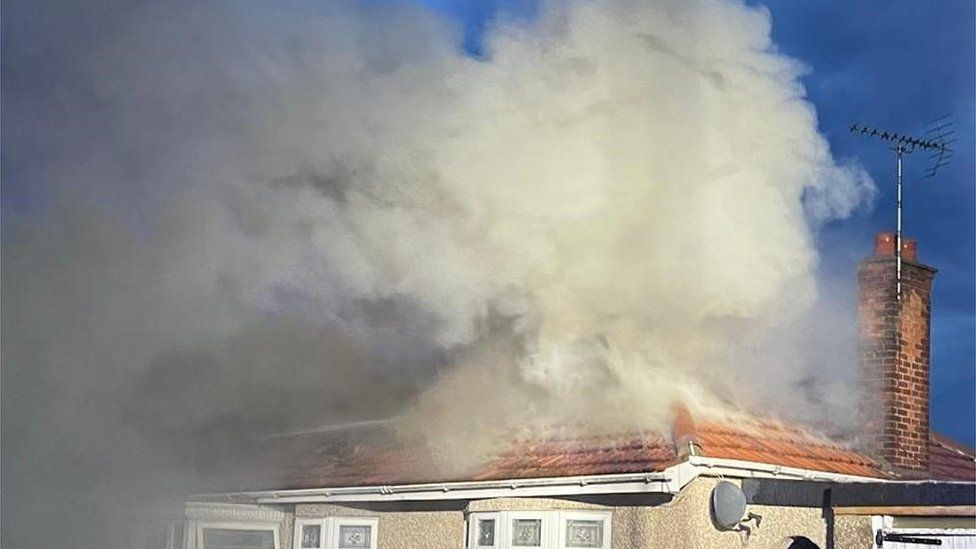 Smoke billowing out of the roof of a bungalow after it caught fire after a lightening strike.