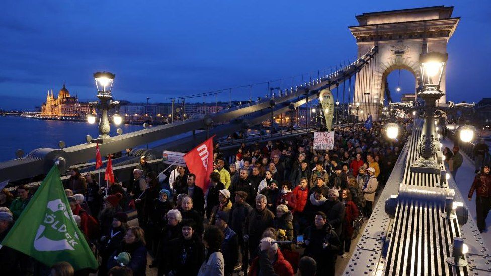 People walk on the Chain Bridge as they take part in a protest to demand the resignation of Hungarian President Katalin Novak