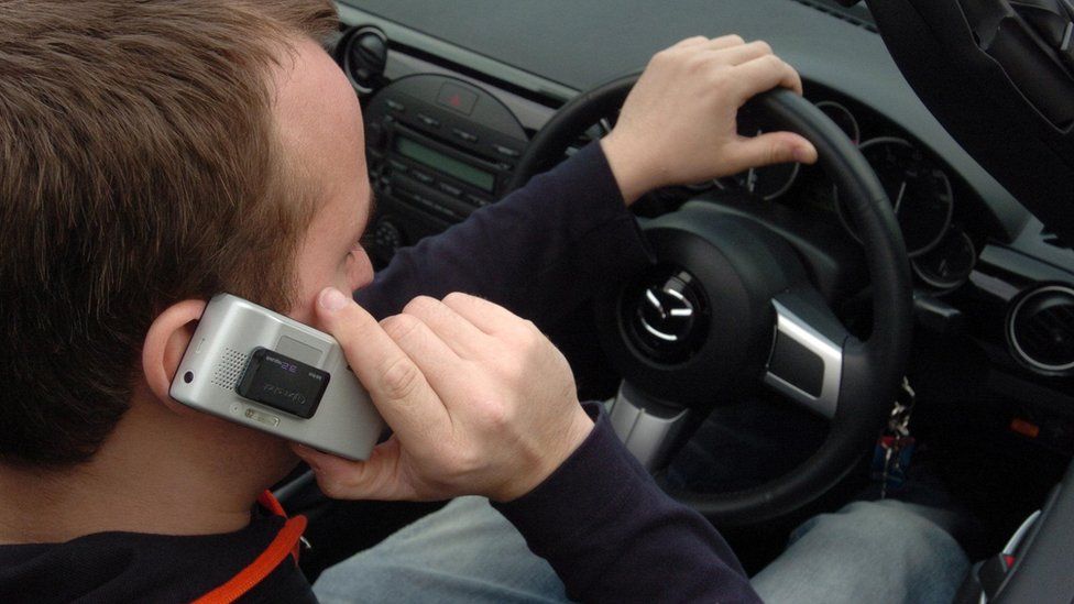 File photo of a man using a mobile phone while driving