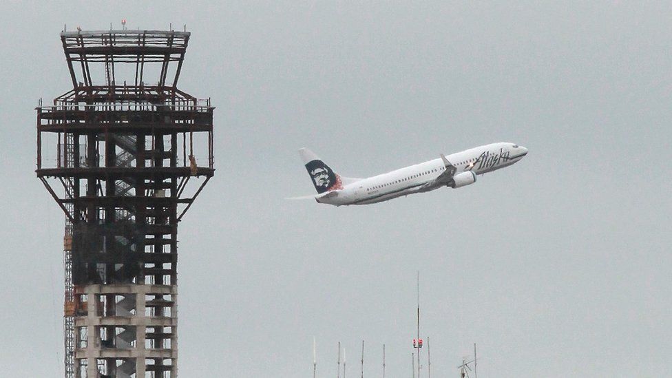 An Alaska Airlines plane takes off past a half-completed 236-foot FAA control tower (L) at Oakland International Airport on July 26, 2011 in Oakland, California.