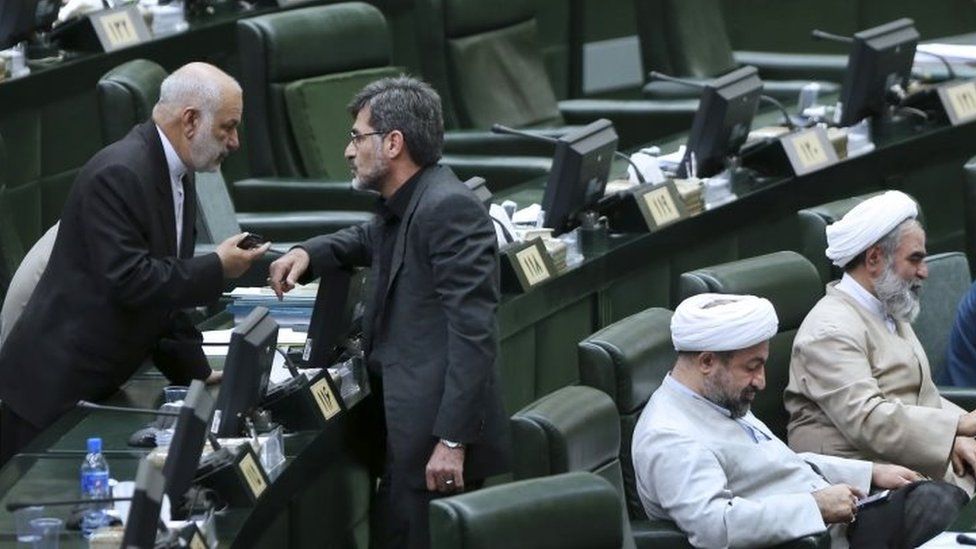 Hardline Iranian lawmaker Mahdi Kouchakzadeh (centre),talks with his colleague Hassan Kamran, as Hamid Rasaei (second right) and Ruhollah Hosseinian sit in an open session of the outgoing parliament in Tehran (01 March 2016)