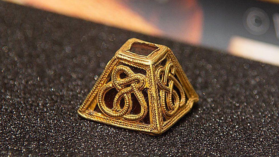 A gold and garnet Anglo-Saxon pyramid mount on a black background