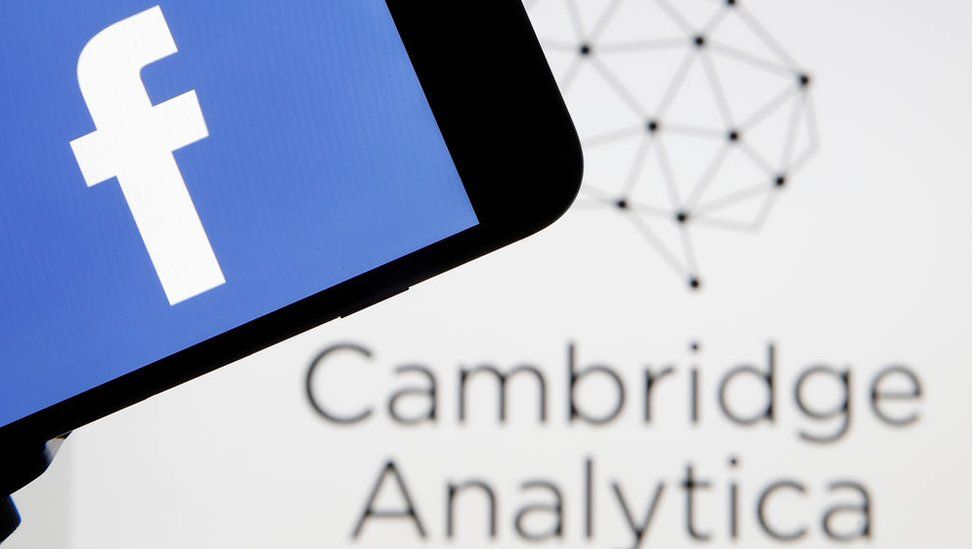 The Facebook logo is seen on a smartphone in front of a Cambridge Analytica logo in this composite shot
