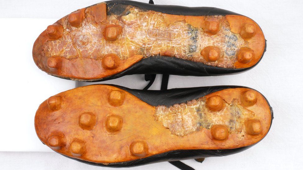 Underside of old football boots with cracked soles and areas of restoration where it looks smoother