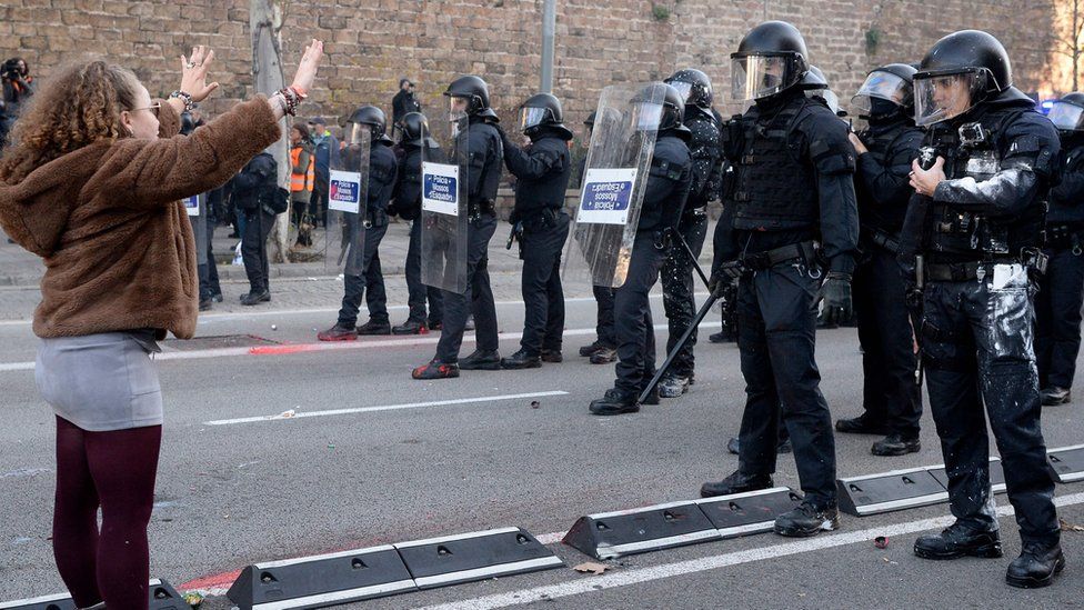 A woman gestures opposite members of the Catalan regional police force in Barcelona on December 21, 2018