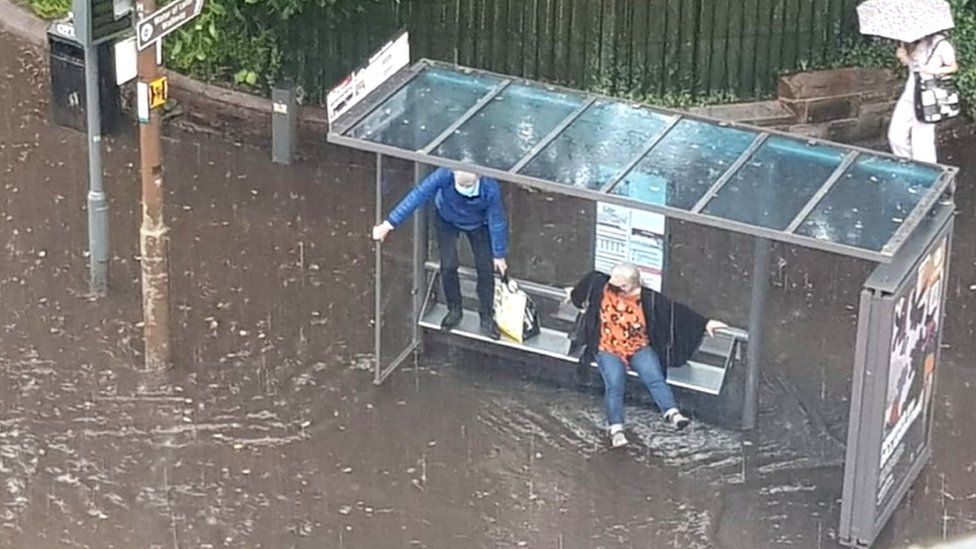 couple stuck in floodwater at bus stop