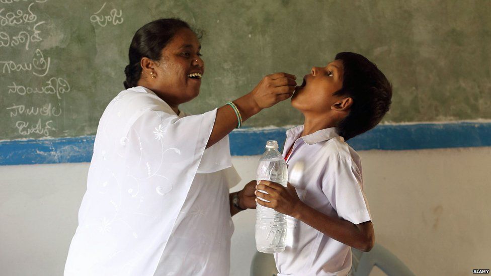 Nurse gives deworming treatment to boy in India