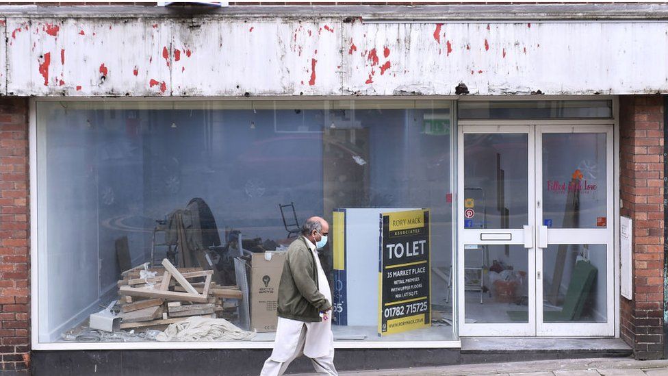 File image of man in a face mask walking past closed business