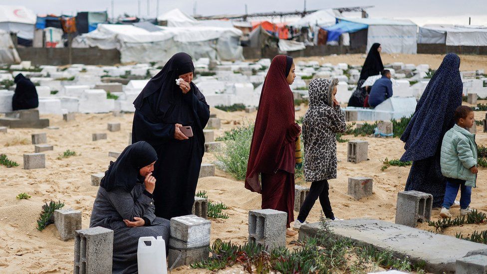 Palestinian women visit graves of relatives killed during the war in Gaza, at a cemetery in Rafah (10 April 2024)