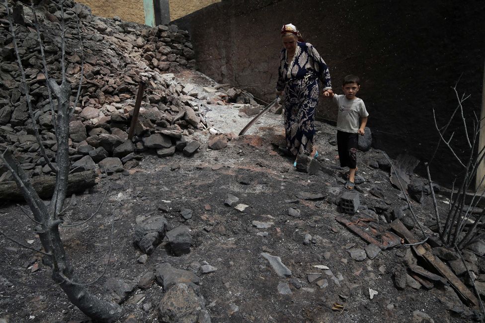 A woman and child walk through burned housed in the village of de Oeud Das in Bejaia in Algeria