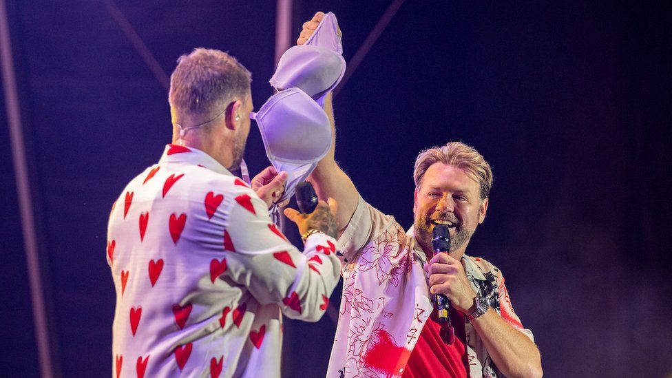 Boyzlife stars Keith Duffy and Brian McFadden hold a bra thrown on to the stage by a member of the audience at their Féile an Phobail concert