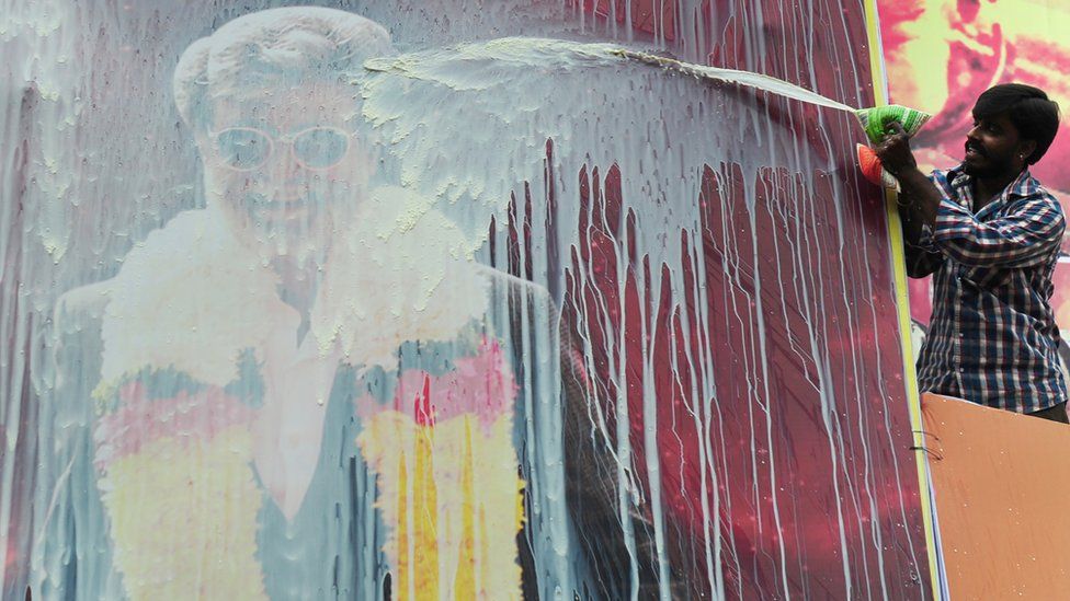 An Indian fan pours milk on a hoarding of Indian movie star, Rajinikanth erected in front of a movie theatre, ahead of the release of his Tamil movie 'Kabali', in Chennai on July 21, 2016