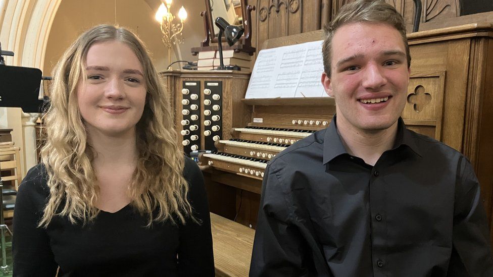 Ellen Taylor and Kyle Bradshaw sit in front of an organ