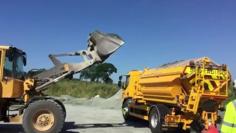 A gritter being filled with sand