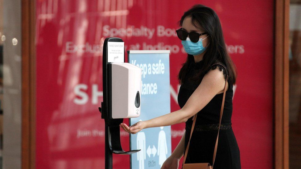 A woman wearing a face mask sanitizes her hand at Yorkdale Shopping Centre on July 7, 2020 in Toronto, Canada.