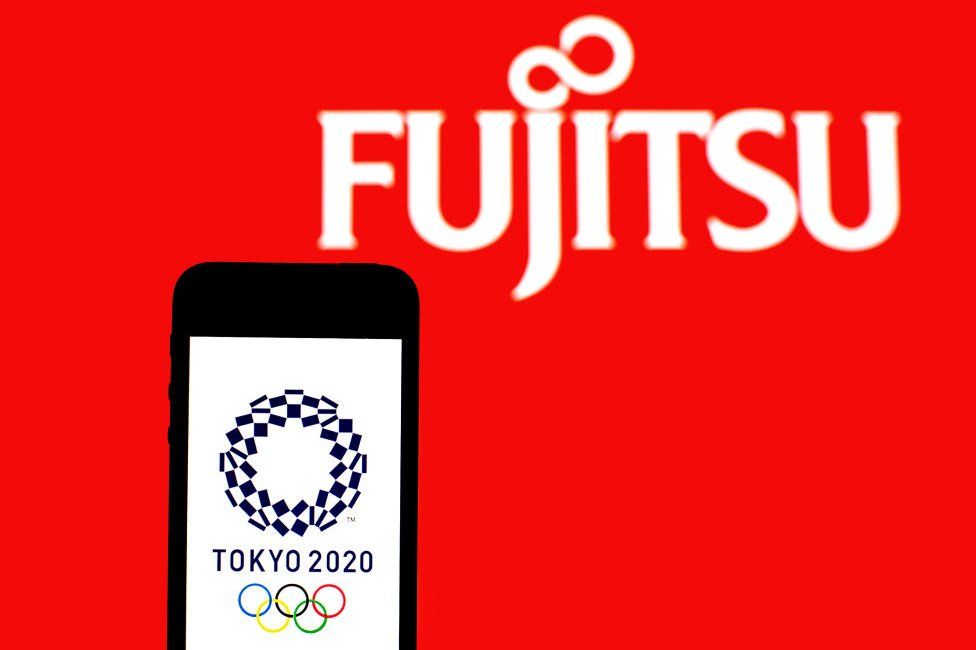 Логотип Tokyo 2020 на экране мобильного телефона с логотипом Fujitsu в фоновом режиме