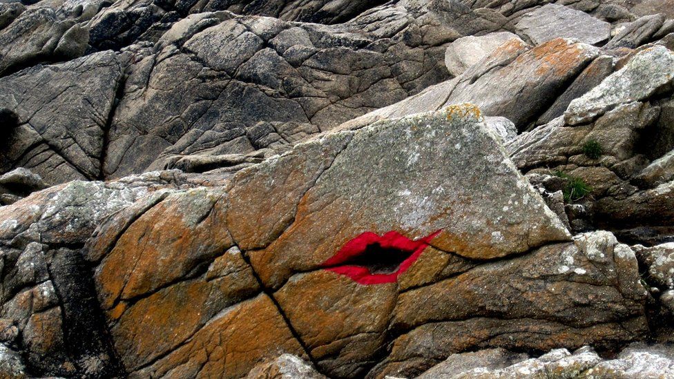 Painted lips on a rock on the coast