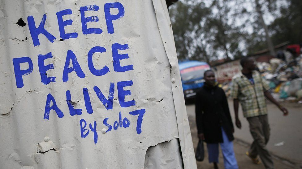 Pedestrians walk in front of a wall with a message of peace painted recently by local street artist Solomon Muyundo, also known as Solo7, on its door in Kibera slum, one of the opposition leader Raila Odinga"s strongholds in the capital Nairobi, Kenya, 23 July 2017.