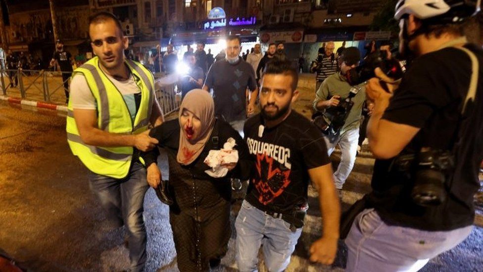 An injured Palestinian woman is led to safety in Jerusalem. Photo: 8 May 2021