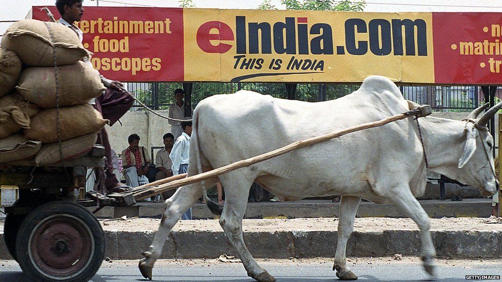 A bullock-driven cart rides past a bus stop billboard advertising one of India's many internet portals 01 June 2000 in New Delhi.