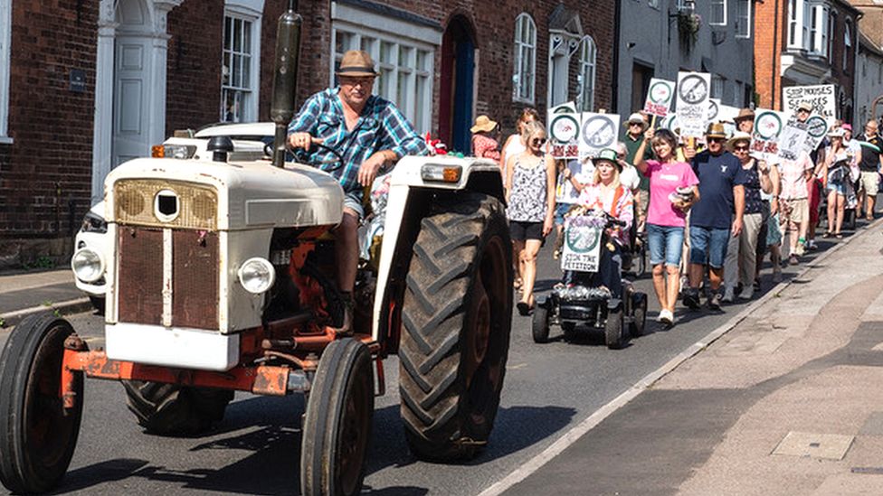 A tractor leading a group of protestors down a road