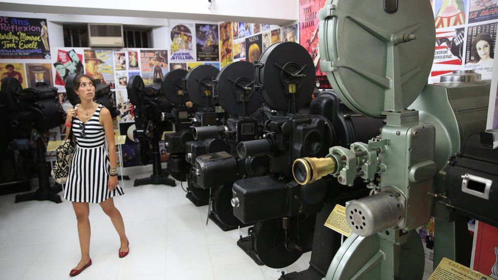 A visitor walks past vintage projectors at the Caliwood Museum