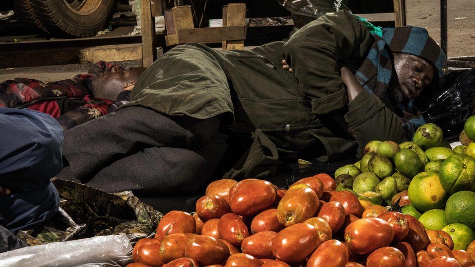 A trader sleeps next to items to be sold at a market following a directive from Ugandan President Yoweri Museveni that all vendors should sleep in markets for 14 days to curb the spread of the COVID-19 coronavirus at Nakasero market in Kampala, Uganda, on April 7, 2020.