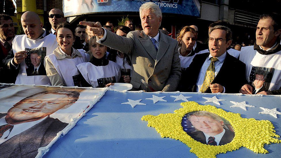 US former President Bill Clinton greets Kosovo Albanians as he stands in front of giant cake made for him during his visit to Pristina on 1 November 2009