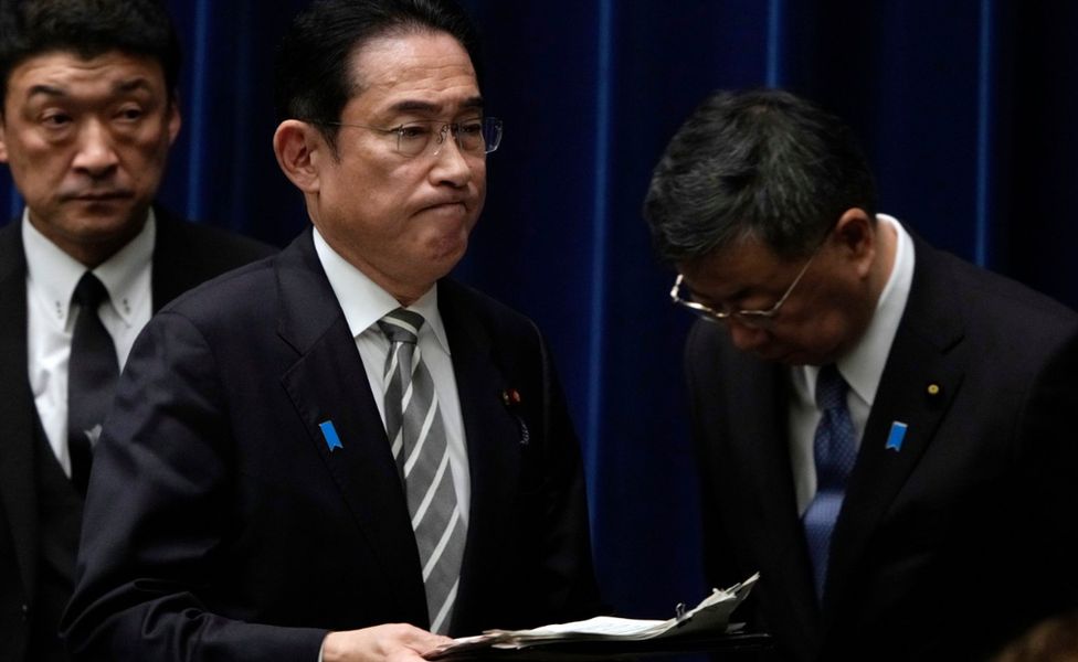 Japanese Prime Minister Fumio Kishida (C) walks past the disgraced Chief Cabinet Secretary Hirokazu Matsuno