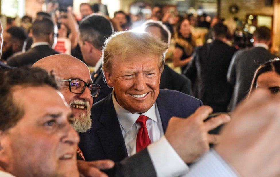 Donald Trump poses with patrons during a surprise visit to the Versailles restaurant in Little Havana, Miami, after pleading not guilty in court