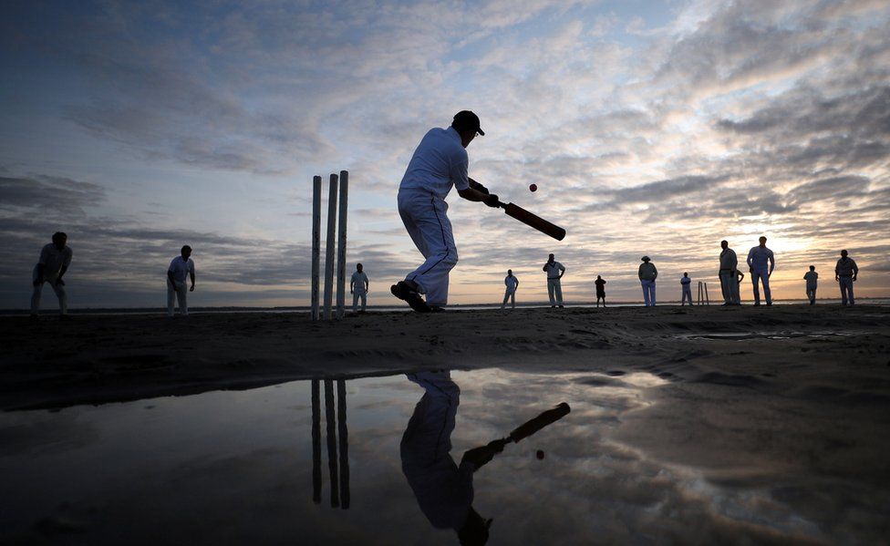A player goes to hit a cricket ball as the sun goes down over the Solent.