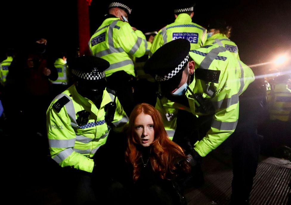 Police detain a woman as people gather at a memorial site