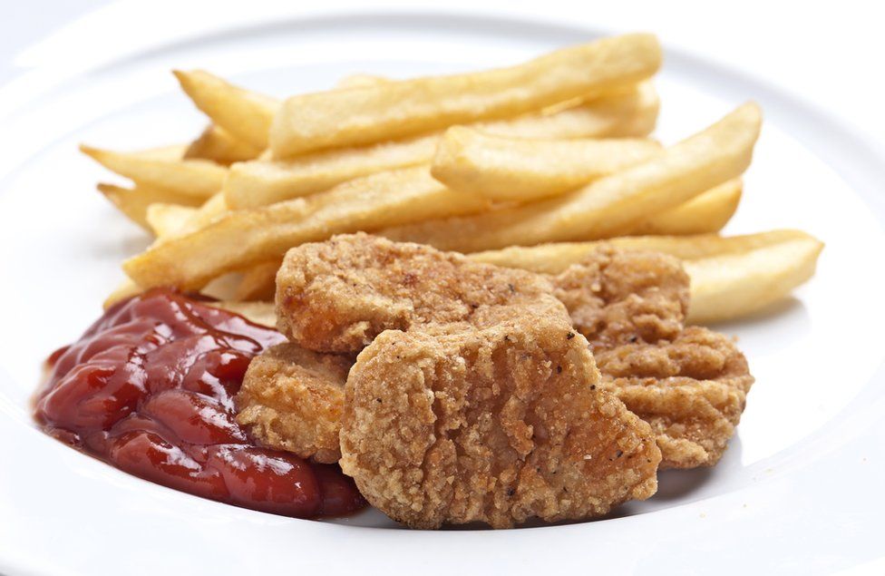 Chicken nuggets and chips on a plate with tomato ketchup